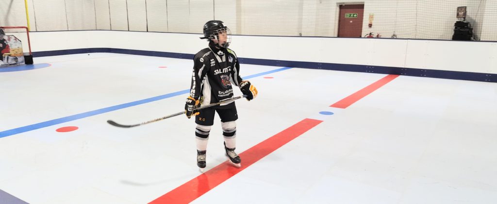 A young hockey player learning how to skate on synthetic ice at home.
